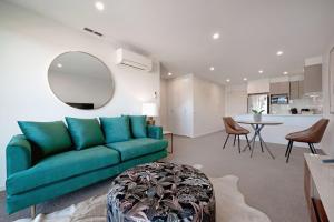 ein Wohnzimmer mit einem grünen Sofa und einer Küche in der Unterkunft The Menzies Suite in Canberra