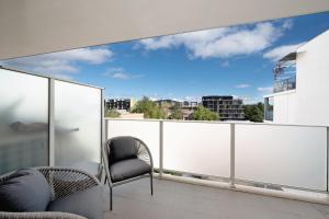 einen Balkon mit 2 Stühlen und Stadtblick in der Unterkunft The Menzies Suite in Canberra
