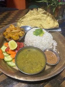 a plate of food with rice and vegetables and dips at Namaste Home Stay in Dhulikhel