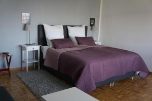 Un dormitorio con una cama grande con sábanas y almohadas púrpuras. en Köln Deutz/Messe, Lanxess Arena, en Colonia