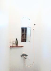 a shower with a hose attached to a wall at ゲストハウス そよ旅 Guesthouse Soyotabi in Ishigaki Island