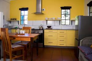 eine Küche mit gelben Wänden, einem Tisch und einem Kühlschrank in der Unterkunft Khayalethu Cottage in Hogsback