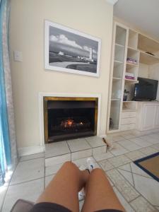 a person laying on the floor in a living room with a fireplace at Port Main Royal Ocean's Edge in St Francis Bay