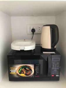 a microwave with a coffee maker on top of it at Homestay Ika KLIA @ Enstek in Kampong Chinchang