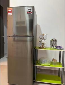 um frigorífico de aço inoxidável numa cozinha ao lado de uma prateleira em Homestay Ika KLIA @ Enstek em Kampong Chinchang