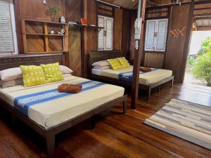 two beds in a room with wooden walls and wood floors at Swiss Cottage Tioman in Tioman Island
