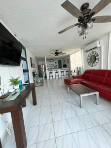 ein Wohnzimmer mit einem roten Sofa und einem Tisch in der Unterkunft Casa Rosado @ Villa Marina Fajardo Pool Yunque in Fajardo