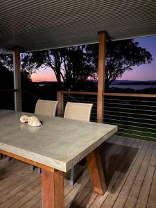 a table and chairs on a deck with a view at Ranges Over the Bay in Culburra Beach