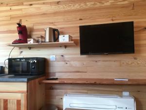 a living room with a tv and a microwave and a kitchen at LA ROULOTTE DE MOUCHOU in Saintes-Maries-de-la-Mer