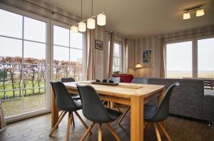 a dining room with a table and chairs and windows at idyllisches Ferienhaus mit eigener Sauna, Kamin und Terrasse - Haus Boddenblick in Vieregge