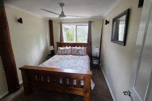 een slaapkamer met een houten bed en een raam bij Nunyara Retreat. Quality bush retreat in Wolfdene +18 foto's