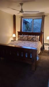 a bedroom with a large wooden bed with a window at Nunyara Retreat. Quality bush retreat in Wolfdene