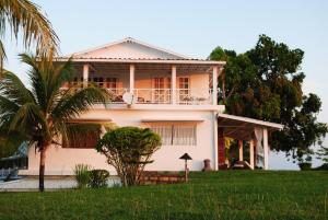 a white house with a palm tree in front of it at camera matrimoniale grande terrazza vista stupenda in Nosy Be