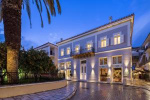 a large white building with a palm tree in front of it at 3 Sixty Hotel & Suites in Nafplio