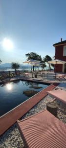 a swimming pool with tables and umbrellas on a beach at Agriturismo Belvedere 9 in La Spezia