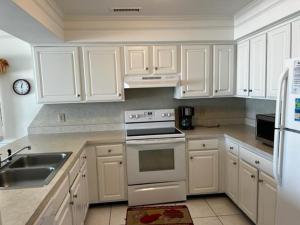 a kitchen with white cabinets and a stove and a sink at South Shores I 3 Condo in Myrtle Beach