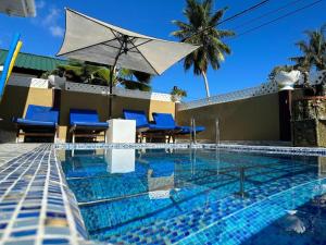 a swimming pool with blue chairs and an umbrella at Happy stay villa in Grand'Anse Praslin