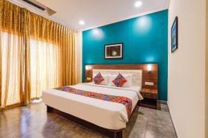 1 dormitorio con 1 cama grande y pared azul en FabHotel Chris, en Bangalore