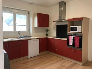 a kitchen with red cabinets and a sink and microwave at Cocon familial dans le Pays Bigouden ! in Plonéour-Lanvern