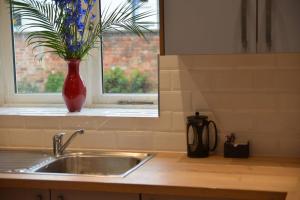 a kitchen sink with a vase of flowers in a window at No. 1 Orange St in Uppingham