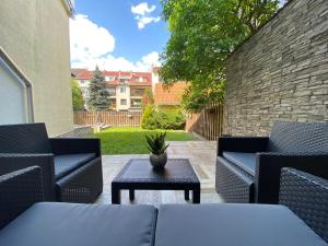 a patio with chairs and a table and a brick wall at Ground Floor Park Bestern in Szeged