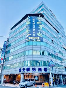 台南的住宿－藍天驛站商務旅館，一座大型玻璃建筑,前面有停车位