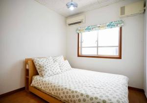 a small bedroom with a bed and a window at Happy House in Kadena