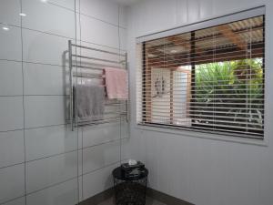 baño con paredes de azulejos blancos y ventana en Blue Wren Studio Apartment, en Currency Creek