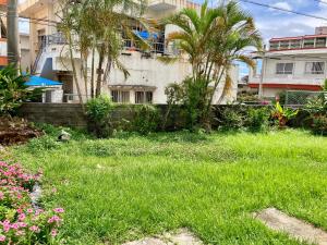 um quintal com relva e palmeiras em frente a um edifício em Happy House em Kadena