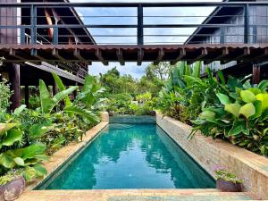 a swimming pool in a garden with a bridge at Chef Nak Luxury Homestay in Phnom Penh