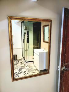 einen Spiegel an der Wand eines Badezimmers mit einem Waschbecken in der Unterkunft Le Grenier, Climatisation Terrasse Wi-Fi Netflix 15 mn coeur de ville in Béziers