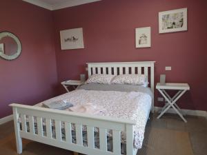 Blue Wren Studio Apartment في Currency Creek: غرفة نوم مع سرير أطفال أبيض وجدران حمراء