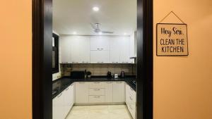 a kitchen with white cabinets and a sign on the door at Olive Service Apartments - Greater Kailash in New Delhi