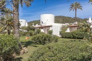 ein weißes Haus mit Palmen und Büschen in der Unterkunft UNIO Ibiza - Adults Only in Cala Vadella