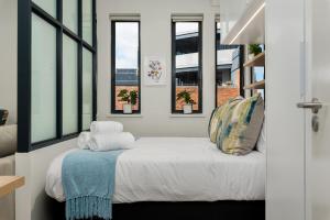 a bedroom with windows and a bed with a blue blanket at The Carrington Aparthotel by Totalstay in Cape Town