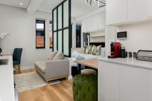 a kitchen and a living room with a table at The Carrington Aparthotel by Totalstay in Cape Town