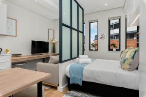 a bedroom with a bed and a desk and windows at The Carrington Aparthotel by Totalstay in Cape Town