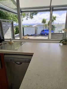 a kitchen with a counter and a view of a car at Adorable Beach Unit Stanmore Bay in Whangaparaoa