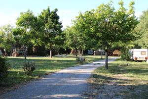 a path in a park with trees and a rv at Habitat Créateur - Hébergements insolites au camping municipal "Les Ecureuils" in Recoubeau