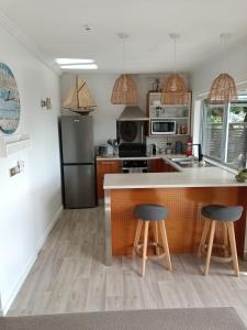 a kitchen with a counter and two stools at Adorable Beach Unit Stanmore Bay in Whangaparaoa