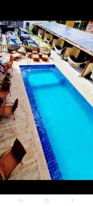 a large blue swimming pool with chairs and tables at Pousada Lua Nova Charmosa Pipa in Pipa