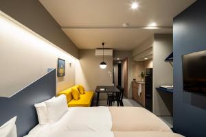 a bedroom with a bed and a yellow couch and a table at Section L Tsukiji in Tokyo