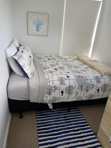 1 dormitorio con 1 cama con manta y alfombra en Adorable Beach Unit Stanmore Bay en Whangaparaoa