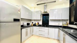 eine Küche mit weißen Schränken und einem Kühlschrank in der Unterkunft Olive Service Apartments - Greater Kailash in Neu-Delhi
