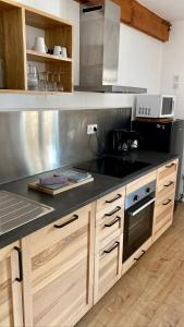 a kitchen with wooden cabinets and a black counter top at Appartement idéal pour été et hiver, situé au pied des pistes de ski et des sentiers de randonnée in Prémanon