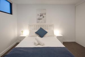 a bedroom with a large white bed with blue pillows at Panorama Apartment Walk to Box Hill Central by GoodLive in Box Hill