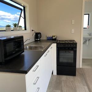 a kitchen with a microwave and a stove and a sink at Tiny Home Farm Stay Retreat in Hikutaia