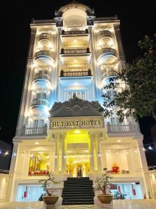 a large white building with a harpy dart hotel at Huy Đạt Hotel in Phan Thiet