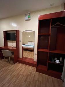 a room with a bed and a desk and a mirror at Rufana Suites in Moalboal