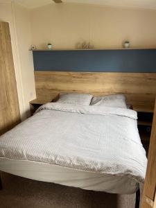 Weymouth bay haven في Preston: غرفة نوم مع سرير أبيض مع اللوح الأمامي الأزرق